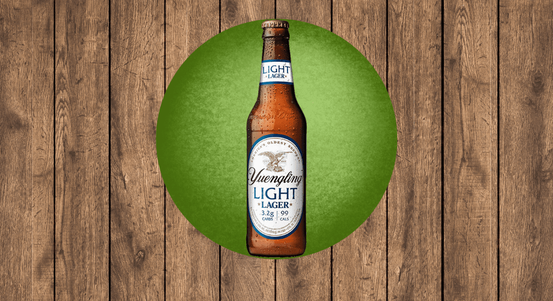 A bottle of Yuengling Light Lager on a green circular background with a wooden texture.